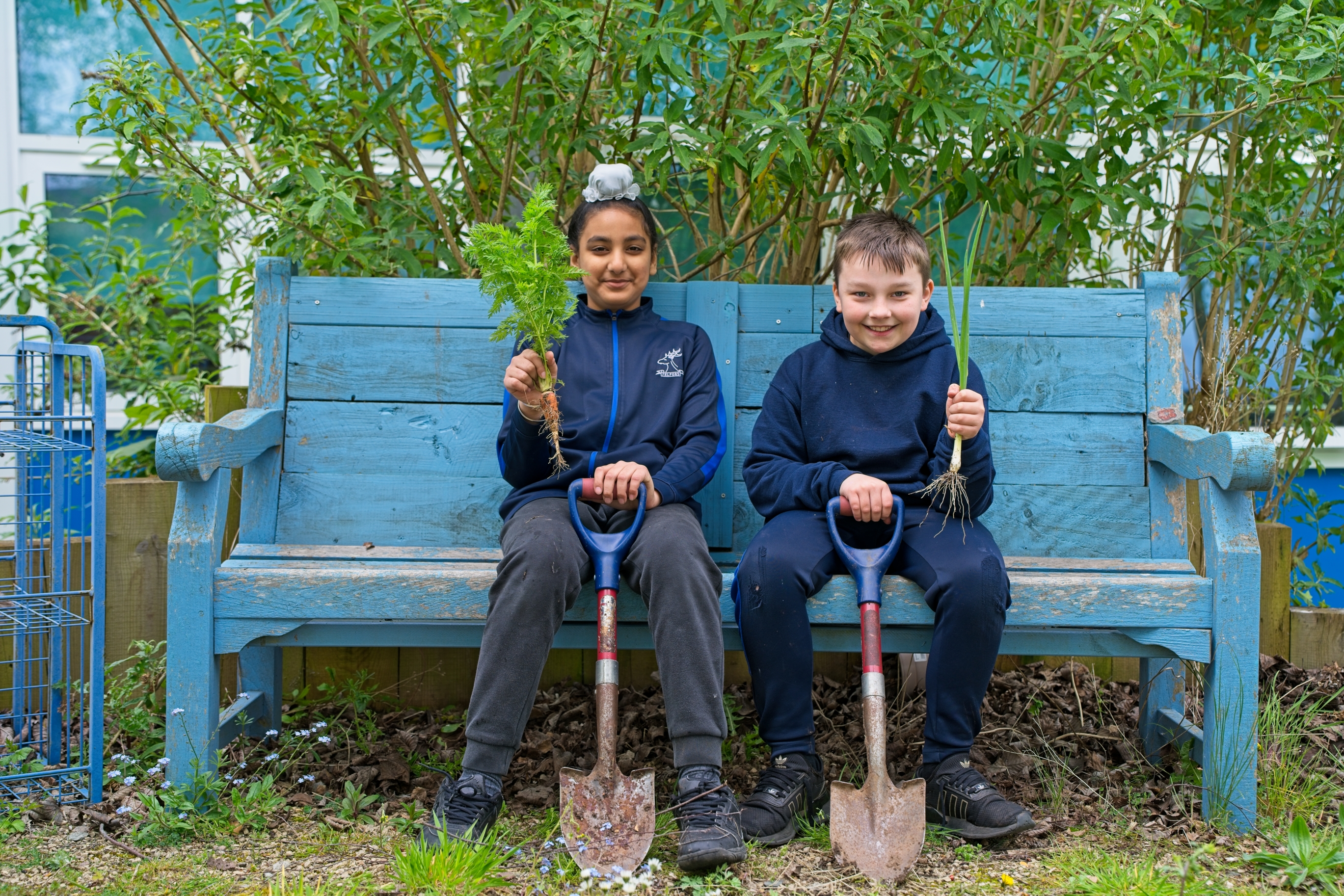 Two Year 6 pupils proudly sharing the vegetables they have grown.