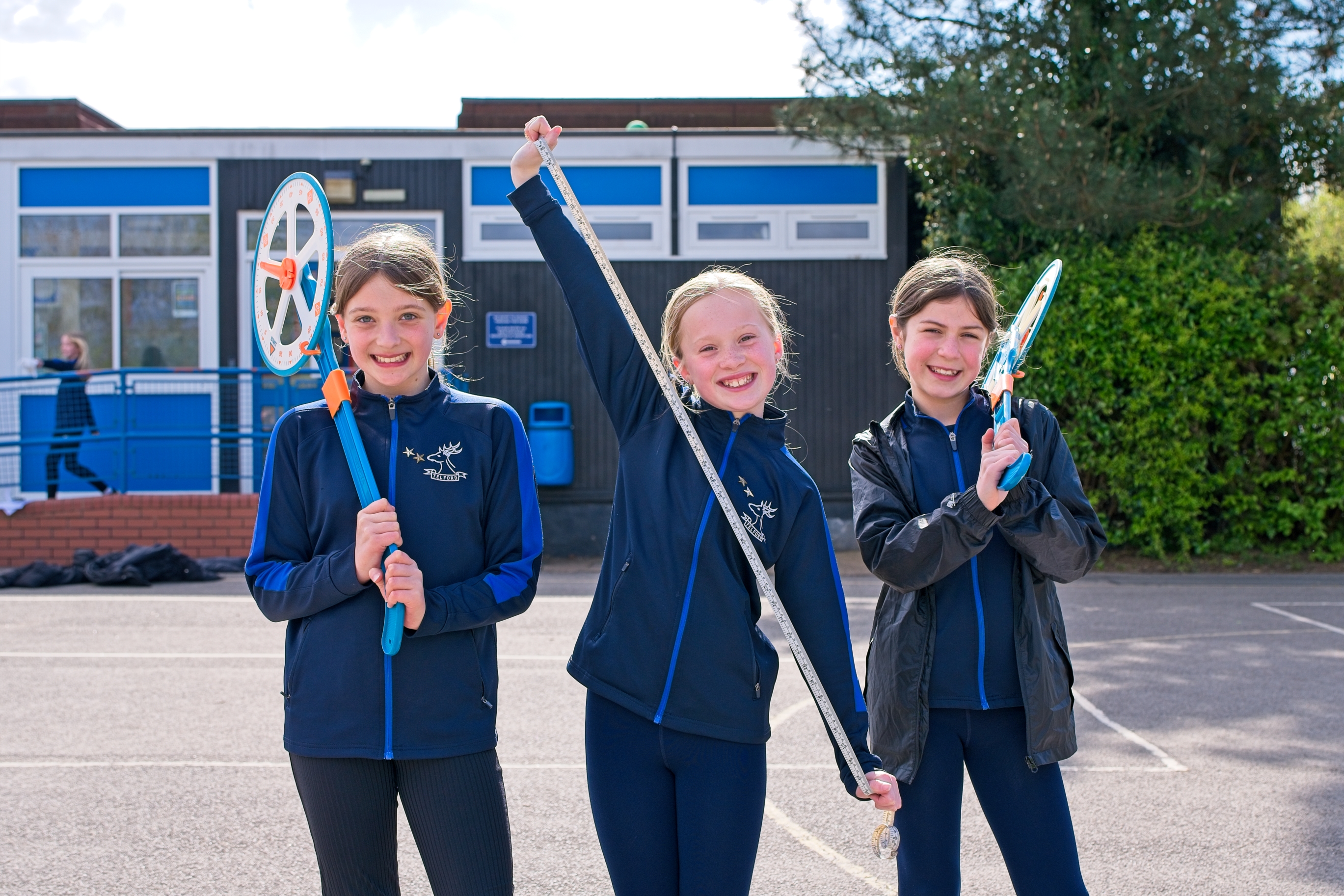 Children measuring distances in the playground using trundle wheels.